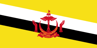 The flag of Brunei has a yellow field with two adjoining diagonal bands of white and black that extend from the upper hoist side of the field to the lower fly side. The red emblem of Brunei is centered on the field.